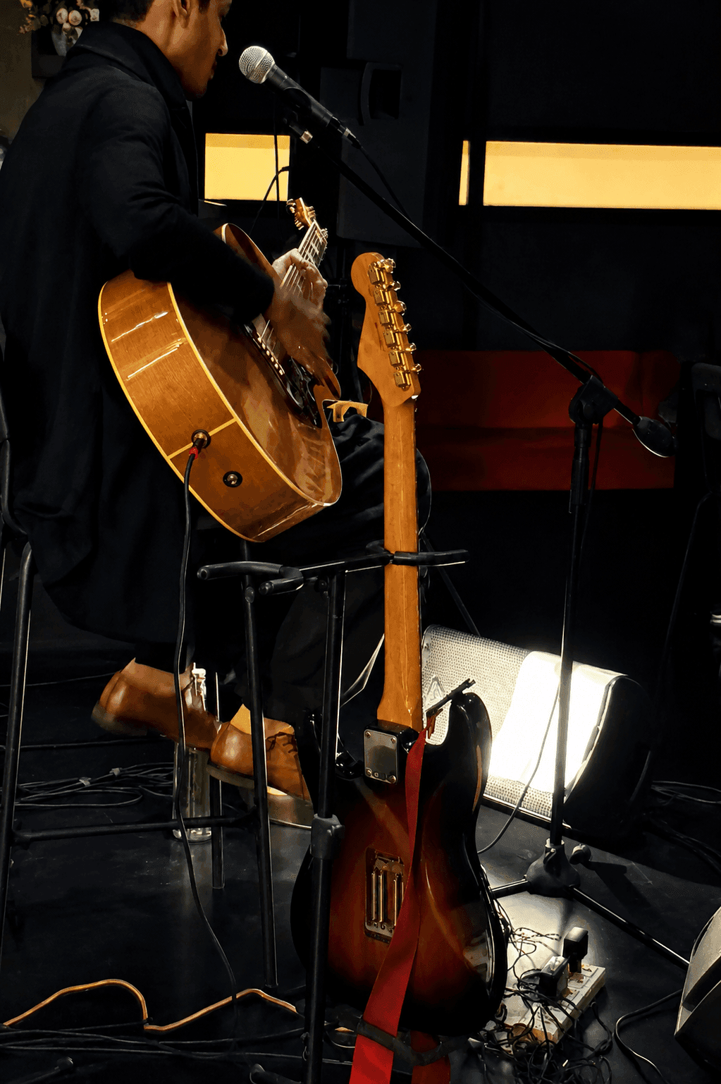 A harmonium-and-guitar duo playing a live set against the night windows